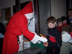 der Nikolaus verteilt Äpfel und Hefe-Nikoläuse